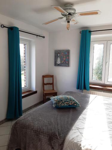a bedroom with a bed with blue curtains and a fan at (La parenthese) in Hombourg