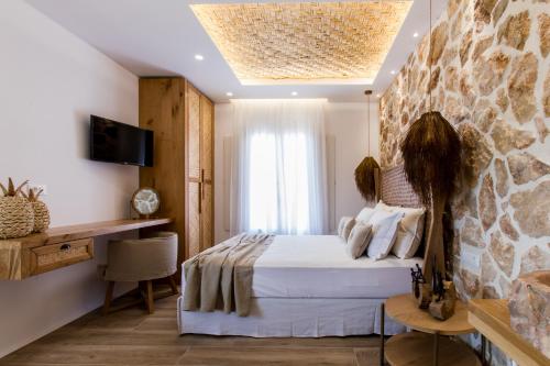 a bedroom with a bed and a stone wall at Arsenis Luxury Villas in Plaka