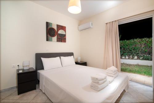 a bedroom with a white bed and a window at SK-George Apartments by the Sea and Airport in Porto Rafti