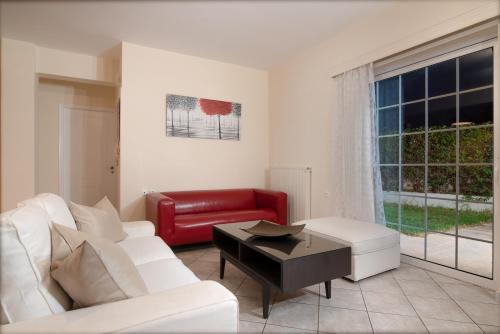 a living room with a white couch and a red chair at SK-George Apartments by the Sea and Airport in Porto Rafti