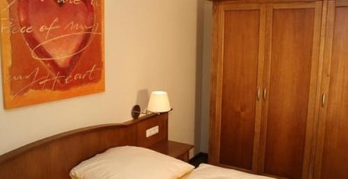 a bedroom with a bed and a cabinet and a picture at Hof Sierksdorf in Sierksdorf