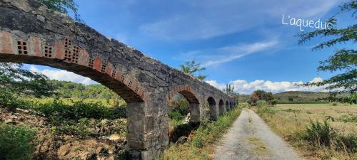 an old stone bridge over a dirt road at Le Coq du Nord - Mailhac Gîte et Chambres d'Hôtes in Mailhac