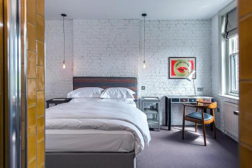 1 dormitorio con cama, escritorio y silla en The Tommyfield Hotel en Londres