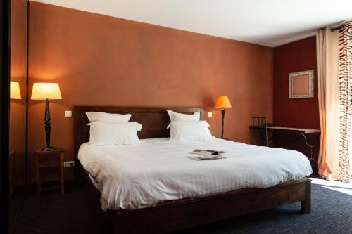 a bedroom with a large bed with white sheets at Hôtel La Gentilhommière in Nuits-Saint-Georges