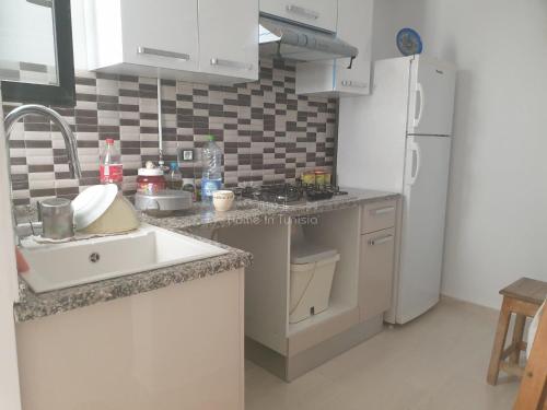 a kitchen with a sink and a white refrigerator at appartement de vacance à corniche in Sousse