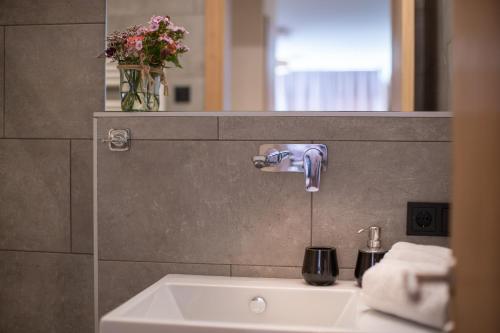 a bathroom sink with a faucet and a mirror at Sunny Ferienwohnungen Ski In - Ski Out - Self Check-in in Zell am See