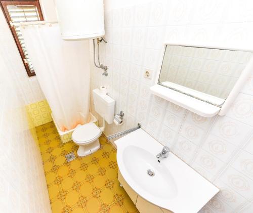 a bathroom with a sink and a toilet and a mirror at Apartments Inga in Novalja