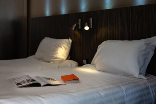 a bed with a book and a magazine on it at Hôtel La Gentilhommière in Nuits-Saint-Georges