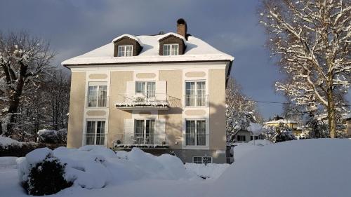 a house covered in snow in front of a yard at The Little Guesthouse in Salzburg