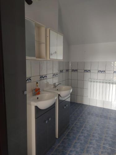 a bathroom with two sinks and a tiled floor at Pokoje u Marii i Piotra in Brzozów