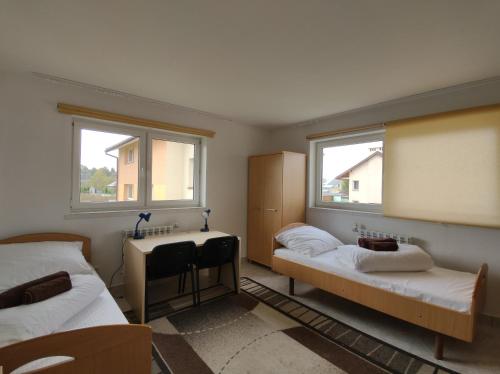 a room with two beds and a desk and two windows at Pokoje u Marii i Piotra in Brzozów