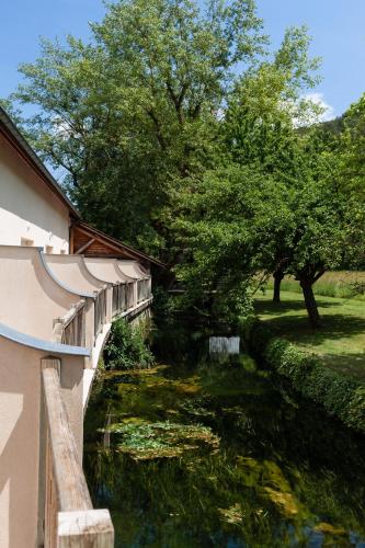 a bridge over a river next to a building at Hôtel La Gentilhommière in Nuits-Saint-Georges