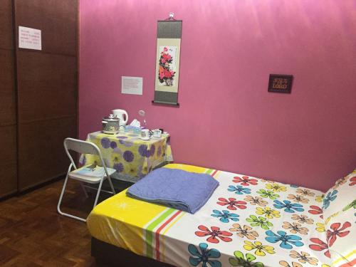 COMFORTABLE MASTERBEDROOM SUITE في سنغافورة: غرفة بسرير وطاولة وجدار وردي