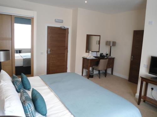 a bedroom with a bed and a desk and a television at Links Hotel in Montrose