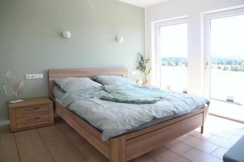 a bedroom with a bed and a large window at Auszeit mit Weitblick in der Sächsischen Schweiz - kleiner Bauernhof mit Tieren und Wallbox in Rathmannsdorf