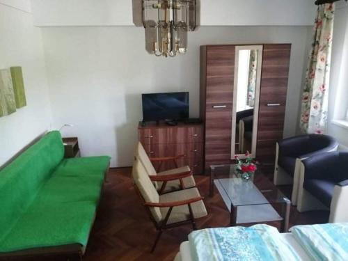 ein Wohnzimmer mit einer grünen Couch und einem Tisch in der Unterkunft Park Apartman in Hajdúszoboszló