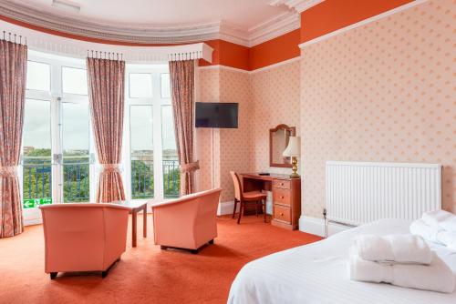 Una habitación de hotel con una cama, un escritorio y una ventana. en The Esplanade Hotel, en Scarborough