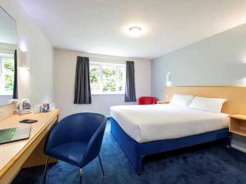a hotel room with a bed and a desk and a computer at ibis budget Dundee Camperdown in Dundee