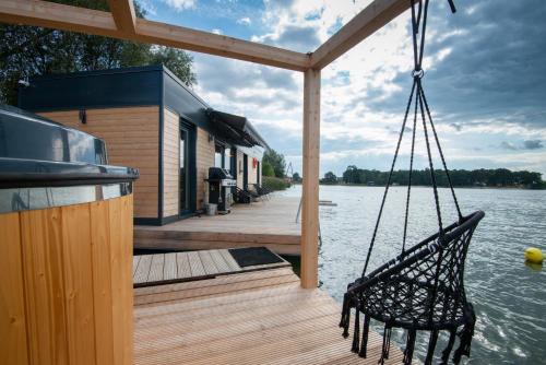 a swing on a dock with a house on the water at Costa del Kryspi Całoroczne Domy na Wodzie in Cholerzyn