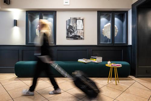 a woman walking through a living room with her luggage at The Midtown Hotel in Cologne