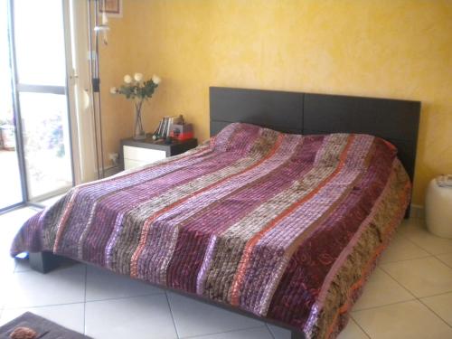 een slaapkamer met een groot bed met een paars dekbed bij Chambre hôtes Wagram in Ajaccio