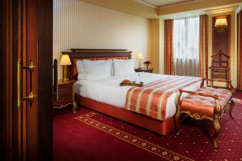 ein Hotelzimmer mit einem großen Bett und einem Stuhl in der Unterkunft Grand Hotel Sofia in Sofia