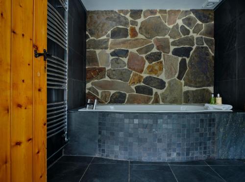 a bathroom with a stone wall and a bath tub at Deer's Leap Retreat in West Anstey