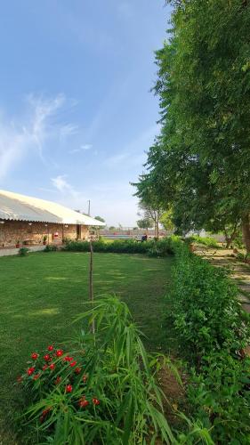 einen grünen Garten mit roten Blumen und einem Gebäude in der Unterkunft The Rustic Villa, a stay with luxuries amenities and exotic nature in Jaipur