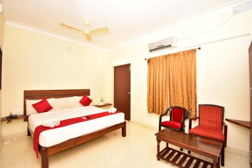 een slaapkamer met een bed en een rode stoel bij Bon Stay Inn in Pondicherry
