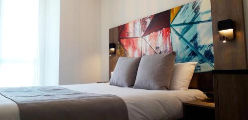 Un dormitorio con una cama con un cuadro en la pared. en Appart-Hôtel Mer & Golf City Bordeaux Lac, en Burdeos