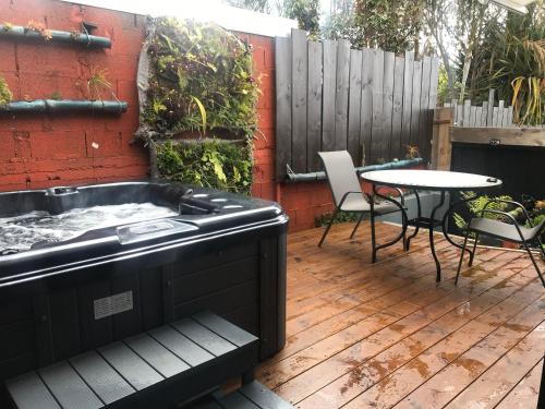 bañera de hidromasaje en una terraza con mesa y sillas en JASMIN DE NUIT - Villa FOURNAISE, en Le Tampon