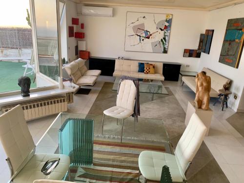 ein Wohnzimmer mit einem Sofa, Stühlen und einem Tisch in der Unterkunft Attico d'arte sulla Valle dei Templi in Agrigento
