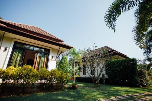 a house with a yard next to a building at Baan Klong Resort in Damnoen Saduak