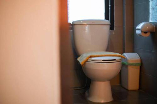 a bathroom with a white toilet with a window at Baan Klong Resort in Damnoen Saduak