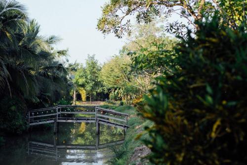 a wooden bridge over a river in a park at Baan Klong Resort in Damnoen Saduak