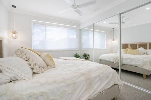 a white bedroom with two beds and a window at Entire Residential Home - Lake Illawarra And Beachside Home Sleeps 12 in Lake Illawarra