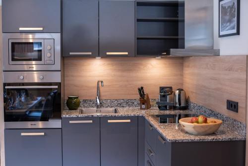 a kitchen with stainless steel appliances and a bowl of fruit at Sunny Ferienwohnungen Ski In - Ski Out - Self Check-in in Zell am See