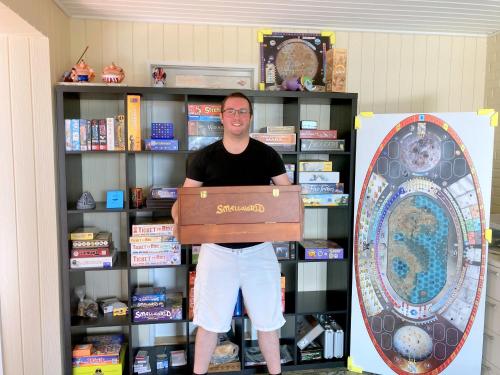 a man standing in a book shelf holding a box at Skovly FerieCenter in Humble