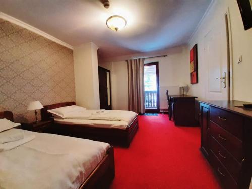 a hotel room with two beds and a red carpet at Dworek Szwajcaria in Zwardoń