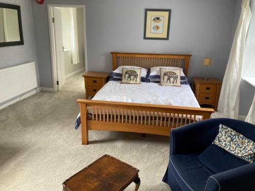 a bedroom with a bed and a blue chair at The Eliot Arms in Saint Germans
