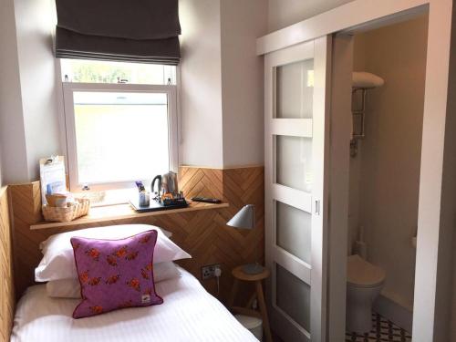 Dormitorio con cama con ventana y almohada en The Broadmead en Falmouth