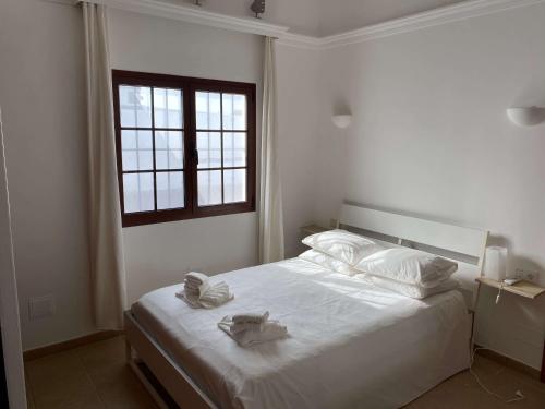 a bedroom with a bed with white sheets and a window at Stunning Villa Arabella - Heated Pool - BBQ - Amazing Terrace - Playa Blanca in Playa Blanca