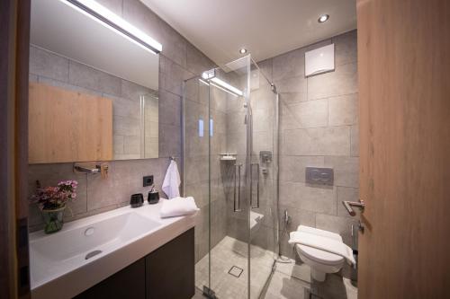 a bathroom with a shower and a toilet and a sink at Sunny Ferienwohnungen Ski In - Ski Out - Self Check-in in Zell am See