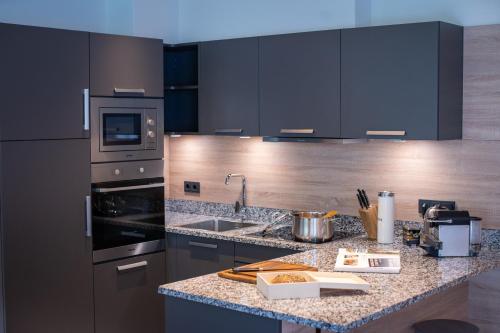 a kitchen with black cabinets and a counter top at Sunny Ferienwohnungen Ski In - Ski Out - Self Check-in in Zell am See