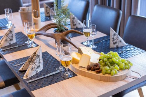 a table with wine glasses and a tray of cheese and grapes at Sunny Ferienwohnungen Ski In - Ski Out - Self Check-in in Zell am See
