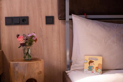 a vase of flowers on a table next to a bed at Sunny Ferienwohnungen Ski In - Ski Out - Self Check-in in Zell am See