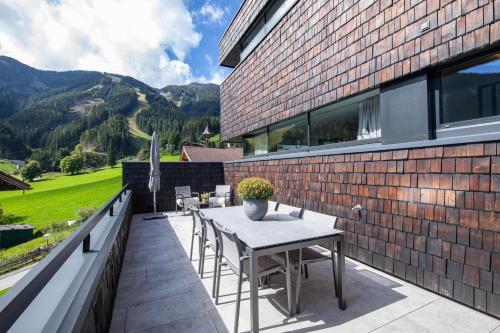a patio with a table and chairs on a brick building at Sunny Ferienwohnungen Ski In - Ski Out - Self Check-in in Zell am See