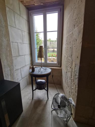 a room with a table and a window and a fan at Les Iris - gîte insolite troglodytique in Trôo