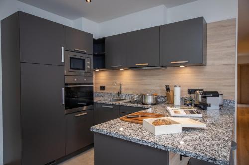 a kitchen with black cabinets and granite counter tops at Sunny Ferienwohnungen Ski In - Ski Out - Self Check-in in Zell am See