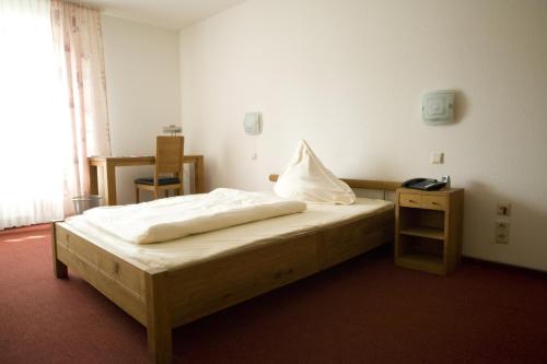 a bedroom with a bed and a table with a phone at Hotel Flora in Dormagen
